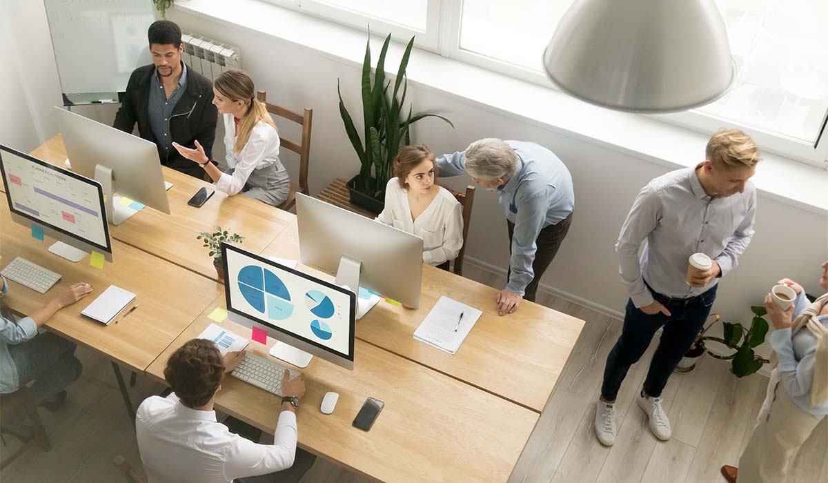 Looking down at a coworking space full of people working together and on computers.
